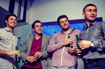 This is a picture of four guys smiling and drinking a few beers at a stag party.